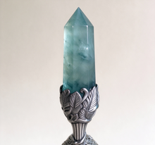 Charger l'image dans la galerie, Close-up of natural fluorite crystal column with faceted translucent surfaces and cloud-like inclusions, set in a carved silver filigree bell holder with floral leaf details – showcasing handcrafted artisan quality