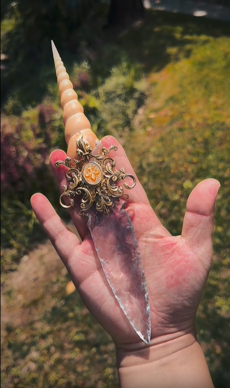 Witch Dagger held over water in a natural outdoor setting, emphasizing its connection to ocean magic and elemental rituals