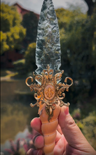 Load image into Gallery viewer, Witch Dagger held over water in a natural outdoor setting, emphasizing its connection to ocean magic and elemental rituals.