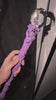 Magic wand placed on a gift box, adorned with purple ribbon and star ornaments, with warm blurred lights in the background.
