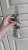 Handcrafted silver filigree bell with natural blue-green fluorite crystal column and iridescent gemstone, held and rotated to show the faceted crystal, carved metal details and leaf-shaped holder – crystal bell wind chime for meditation, home décor and gifting
